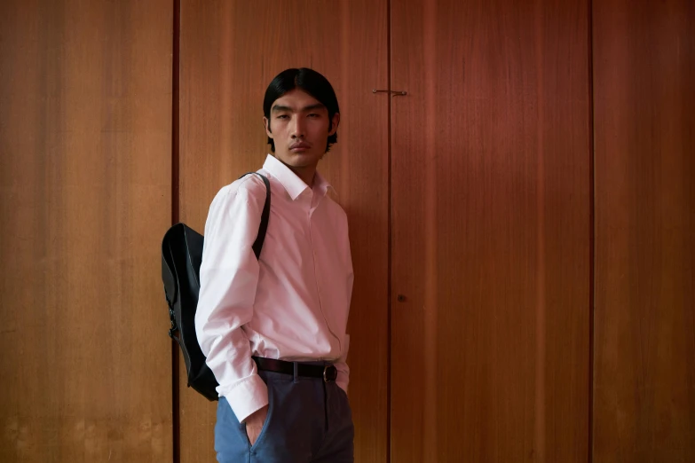 a man standing in front of a wooden wall, an album cover, unsplash, shin hanga, wearing school uniform, mark edward fischbach, ignant, with a backpack