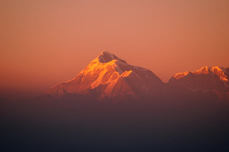 a plane flying over a snow covered mountain range, pexels contest winner, sumatraism, red and orange glow, nepal, standing in front of a mountain, in a sunset haze