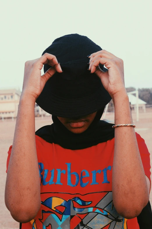 a person in a red shirt and a black hat, inspired by René Burri, trending on unsplash, symbolism, black teenage girl, burberry, ((blue)), hijab