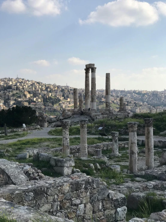 a group of columns sitting on top of a lush green hillside, in a ruined cityscape, square, photo on iphone, arabic