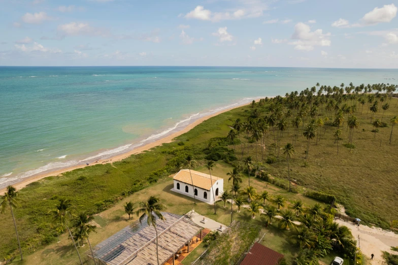 a house sitting on top of a lush green field next to the ocean, by Felipe Seade, beach on the outer rim, bolsonaro, museum photo, slide show