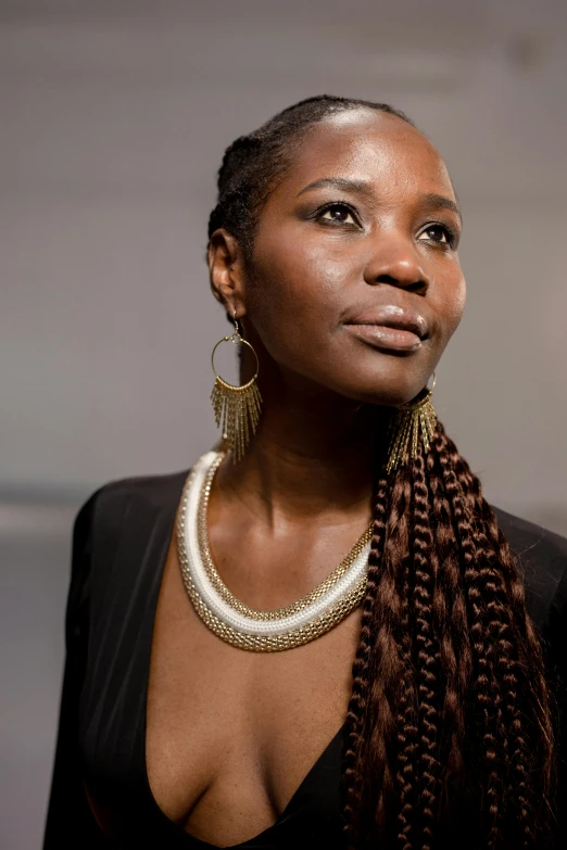 a woman in a black dress posing for a picture, by Lily Delissa Joseph, trending on unsplash, afrofuturism, long braided hair pulled back, intricate african jewellery, woman with braided brown hair, adut akech