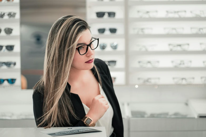 a woman sitting at a table with a laptop in front of her, by Carey Morris, trending on pexels, hurufiyya, glasses frames, at the counter, elegantly dressed, alex yanes