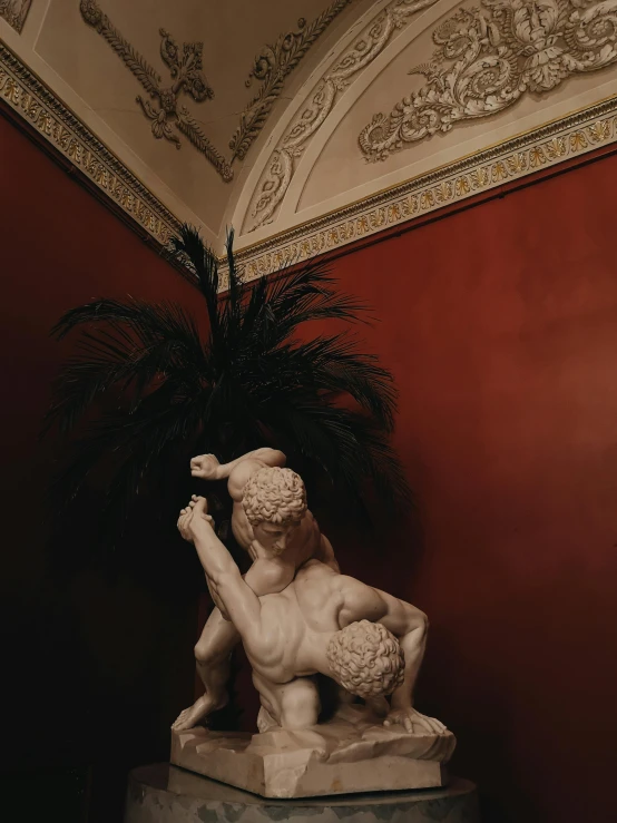 a statue sitting on top of a table next to a plant, inspired by Gustave Boulanger, pexels contest winner, mannerism, fighting each other, marble room, done in the style of caravaggio, putti