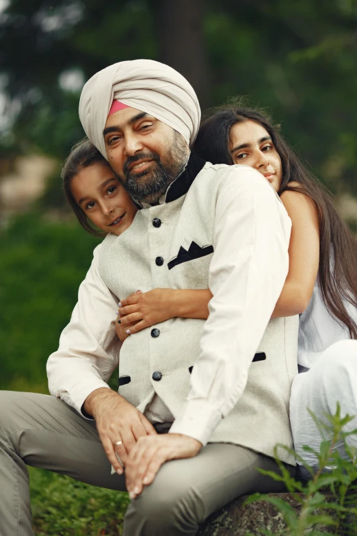 a man in a turban sitting next to a woman, an album cover, inspired by Sardar Sobha Singh, pexels, father with child, hugging, portrait of family of three, still from a music video