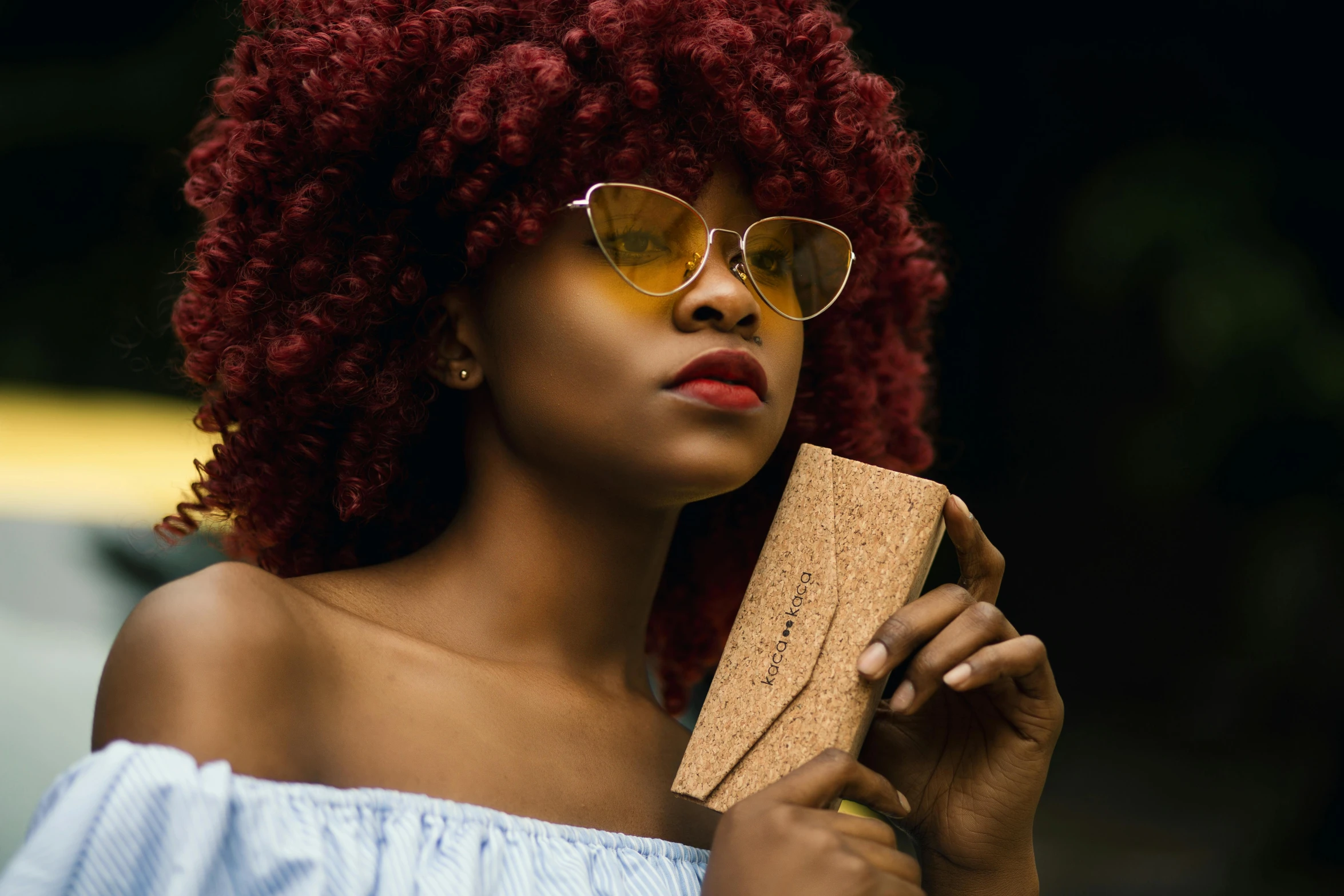 a woman with red curly hair holding a wallet, inspired by Afewerk Tekle, trending on pexels, wearing gold glasses, mahogany wood, avatar image, natural hair