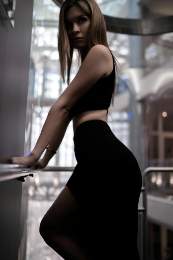 a woman in a black dress leaning on a railing, inspired by Elsa Bleda, pexels contest winner, arabesque, tight outfit, in a gym, mini skirt, {perfect body}