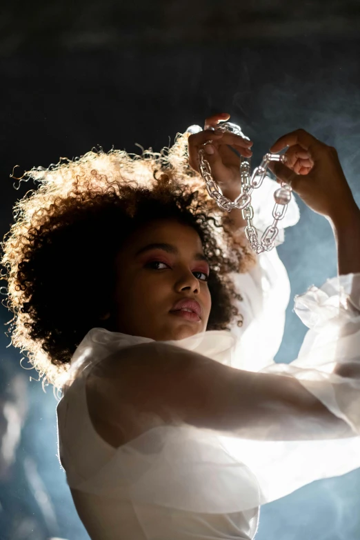 a woman in a white dress holding a bottle of water, an album cover, by Lily Delissa Joseph, pexels contest winner, thick glowing chains, imaan hammam, shot at dark with studio lights, holding a crystal ball