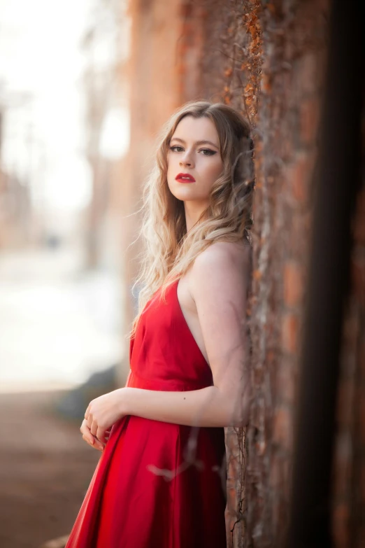 a woman in a red dress leaning against a wall, by Sam Black, renaissance, aurora aksnes, pale skin curly blond hair, josh grover, square