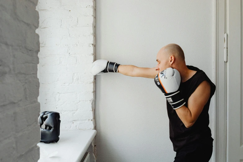 a man standing in front of a window wearing boxing gloves, a photo, by Emma Andijewska, pexels contest winner, working out, in front of a round, profile image, stretching to walls