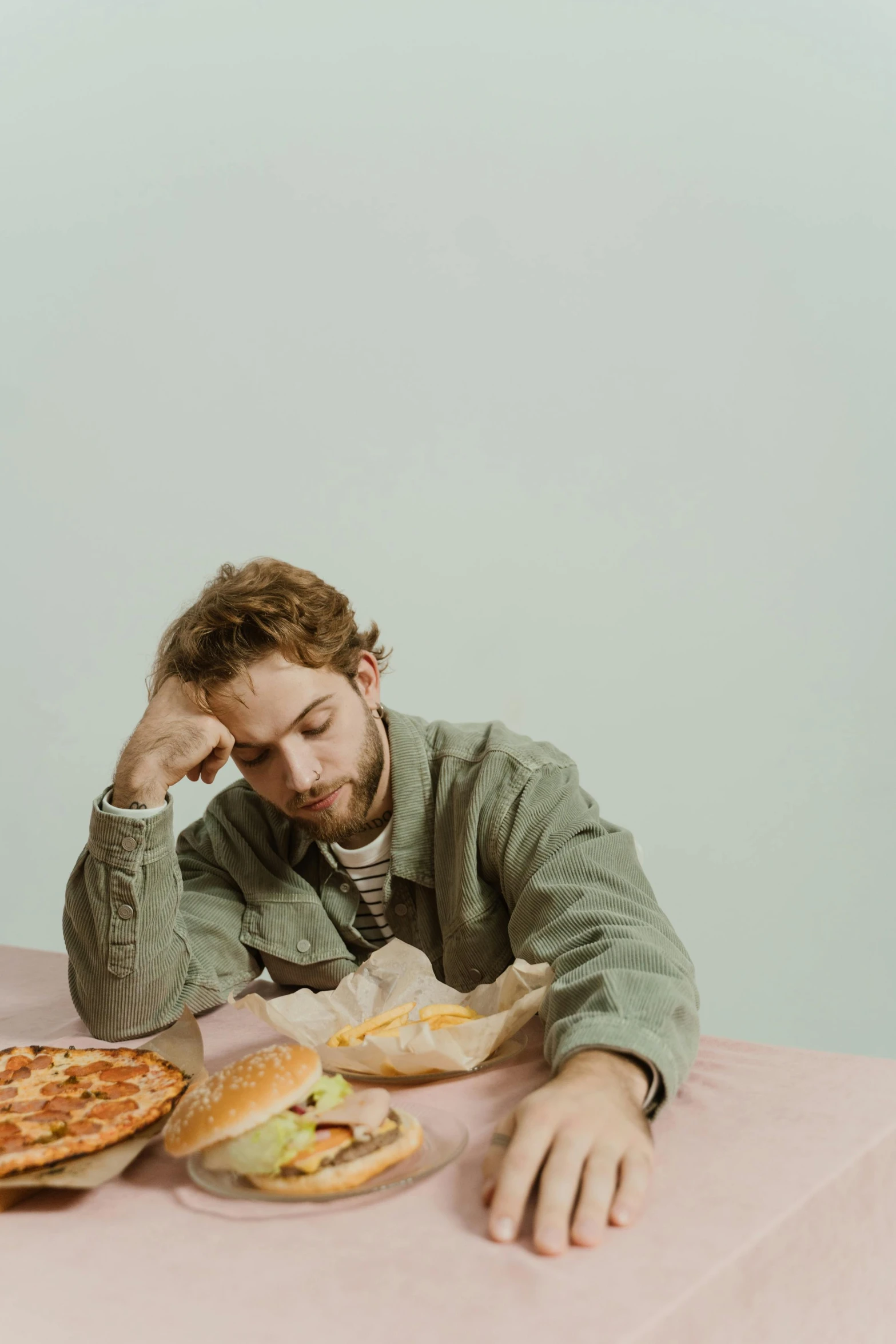 a man sitting at a table with a plate of pizza, an album cover, by Elsa Bleda, trending on pexels, charlie cox, sad face, 15081959 21121991 01012000 4k, on a pale background