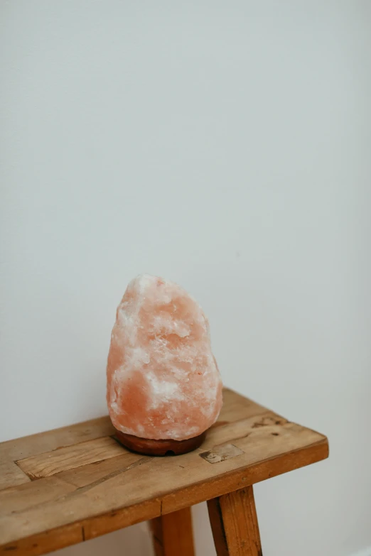 a pink rock sitting on top of a wooden table, a marble sculpture, himalayan rocksalt lamp, straight on portrait, 6 0 0 mm, lightweight