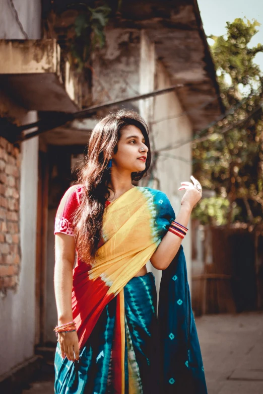 a woman in a colorful sari standing in front of a building, pexels contest winner, handsome girl, 256435456k film, casually dressed, very expressive