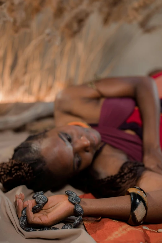 a woman laying on top of a bed next to a laptop, afrofuturism, himba hairstyle, wearing shipibo tattoos, close - up photograph, concerned