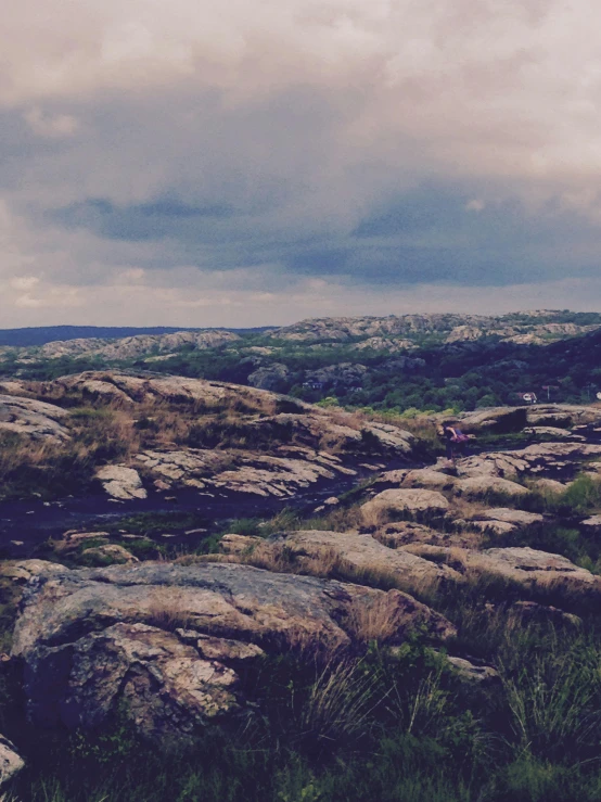 a herd of sheep standing on top of a lush green hillside, an album cover, by Jesper Knudsen, unsplash, happening, with lots of dark grey rocks, panoramic view of girl, low quality footage, archipelago