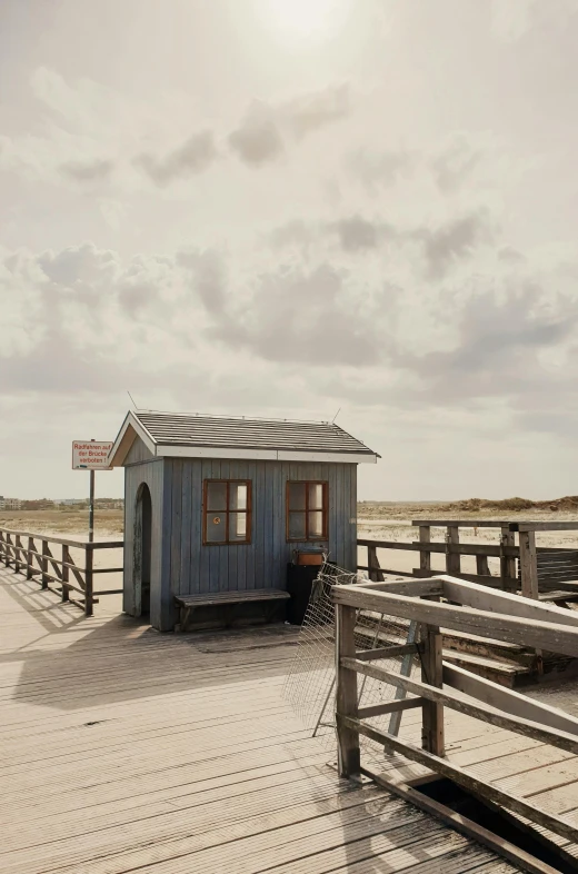 a blue house sitting on top of a wooden pier, a colorized photo, unsplash, photorealism, the netherlands, gazebos, 2022 photograph, medium format