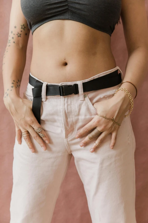 a woman standing with her hands in her pockets, trending on pexels, adonis belt, black white pastel pink, queer woman, close up front view