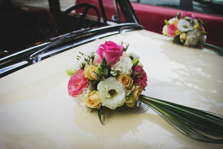 a bouquet of flowers sitting on the hood of a car, inspired by Allan Ramsay, unsplash, romanticism, pink and yellow, vintage cars, wedding, convertable