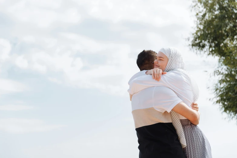 a couple of people that are hugging each other, pexels contest winner, hurufiyya, white hijab, midsommar, background image, from a distance