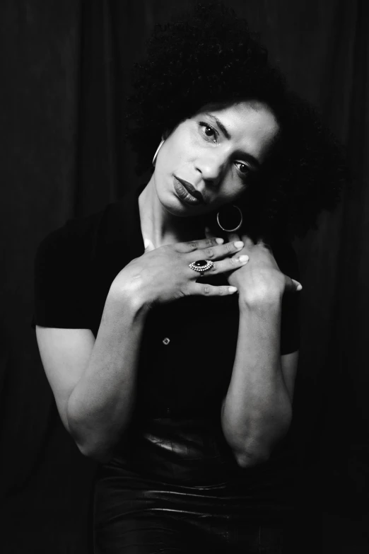 a black and white photo of a woman, inspired by Carrie Mae Weems, hands crossed, prince, grungy woman, she is facing the camera