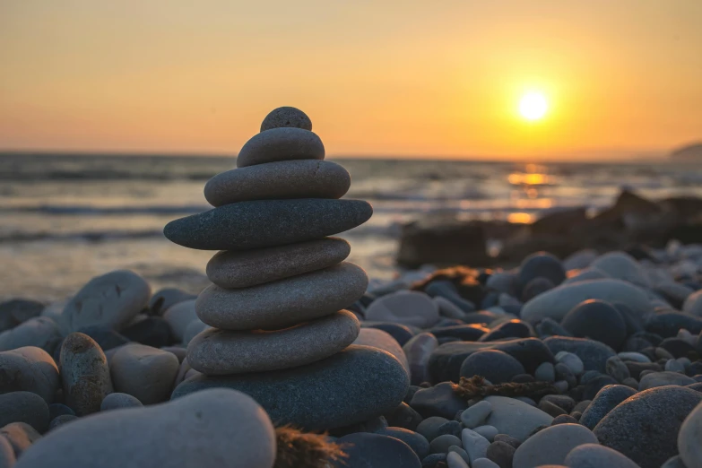 a stack of rocks sitting on top of a rocky beach, unsplash, sun setting, health spa and meditation center, grey, circle