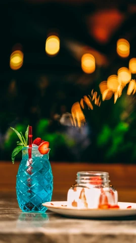 a close up of a plate of food on a table, a still life, unsplash, colorful coctail, teal lights, lush plants and lanterns, blue and red color scheme