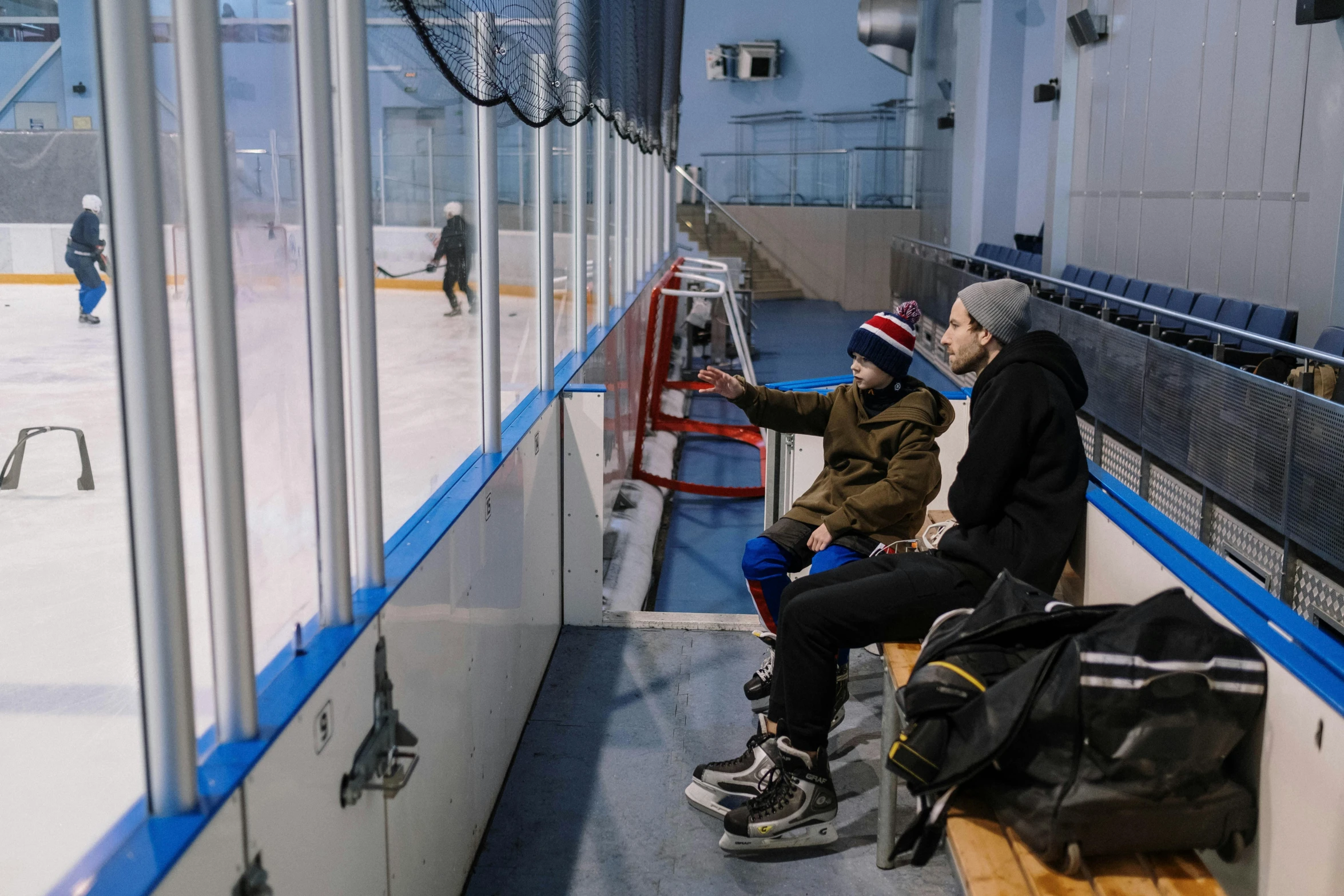 a couple of people that are sitting on a bench, full ice hockey goalie gear, parents watching, alessio albi, february)