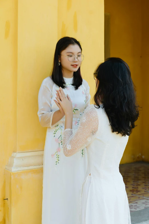 a woman in a white dress standing next to a woman in a white dress, inspired by Ruth Jên, pexels contest winner, ao dai, admiring her own reflection, square, ( ( theatrical ) )