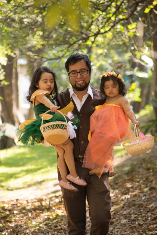 a man holding two little girls in a park, inspired by Kate Greenaway, wearing cave man clothes, manila, with an easter basket, production photo