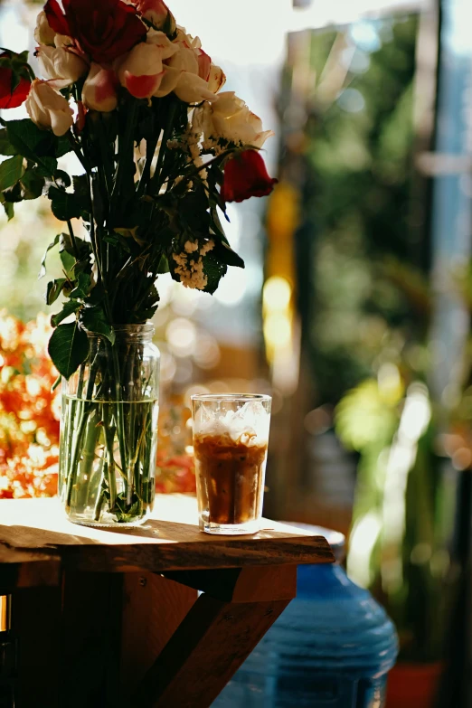 a vase of flowers sitting on top of a table, unsplash, romanticism, tall iced tea glass, sun drenched, small hipster coffee shop, cold brew coffee )