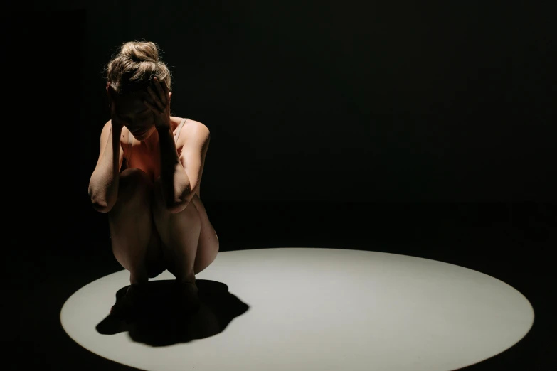 a woman sitting on top of a white table, inspired by Vanessa Beecroft, unsplash, video art, crawling out of a dark room, all enclosed in a circle, looking sad, shadow play