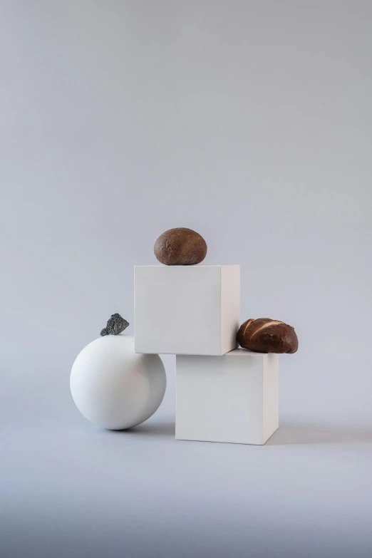 a couple of balls sitting on top of a white cube, inspired by Isamu Noguchi, new sculpture, oak acorns, brown ) ), small in size, seeds