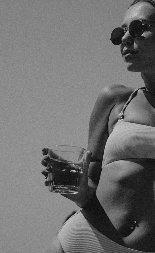 a woman in a bikini holding a glass of water, a black and white photo, unsplash, renaissance, sport bra and shirt, showstudio, in style of petra collins, 2 0 0 0's photo