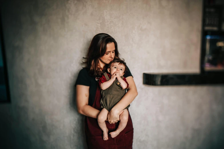 a woman holding a baby in her arms, a portrait, by Emma Andijewska, pexels contest winner, wearing overalls, thumbnail, colour photo, lachlan bailey