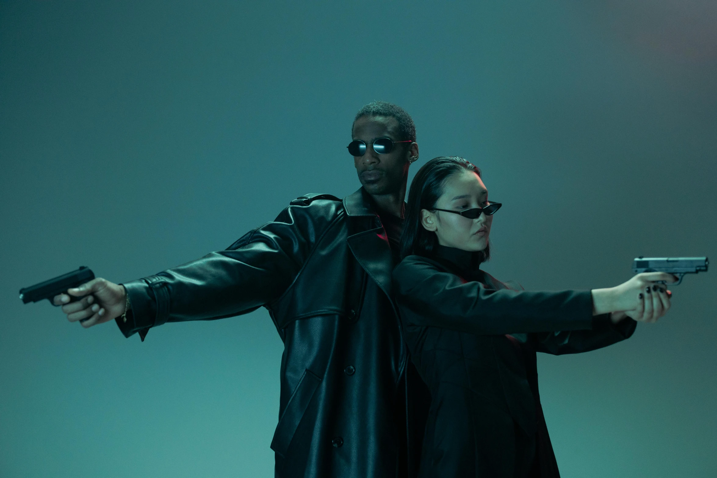 a man standing next to a woman holding a gun, an album cover, trending on pexels, bauhaus, all black cyberpunk clothes, with sunglass, yeezy collection, cinematic outfit photo