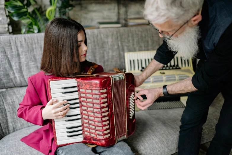 an older man playing an accordion with a young girl, by Julia Pishtar, pexels contest winner, maroon, australian, holding an epée, organs