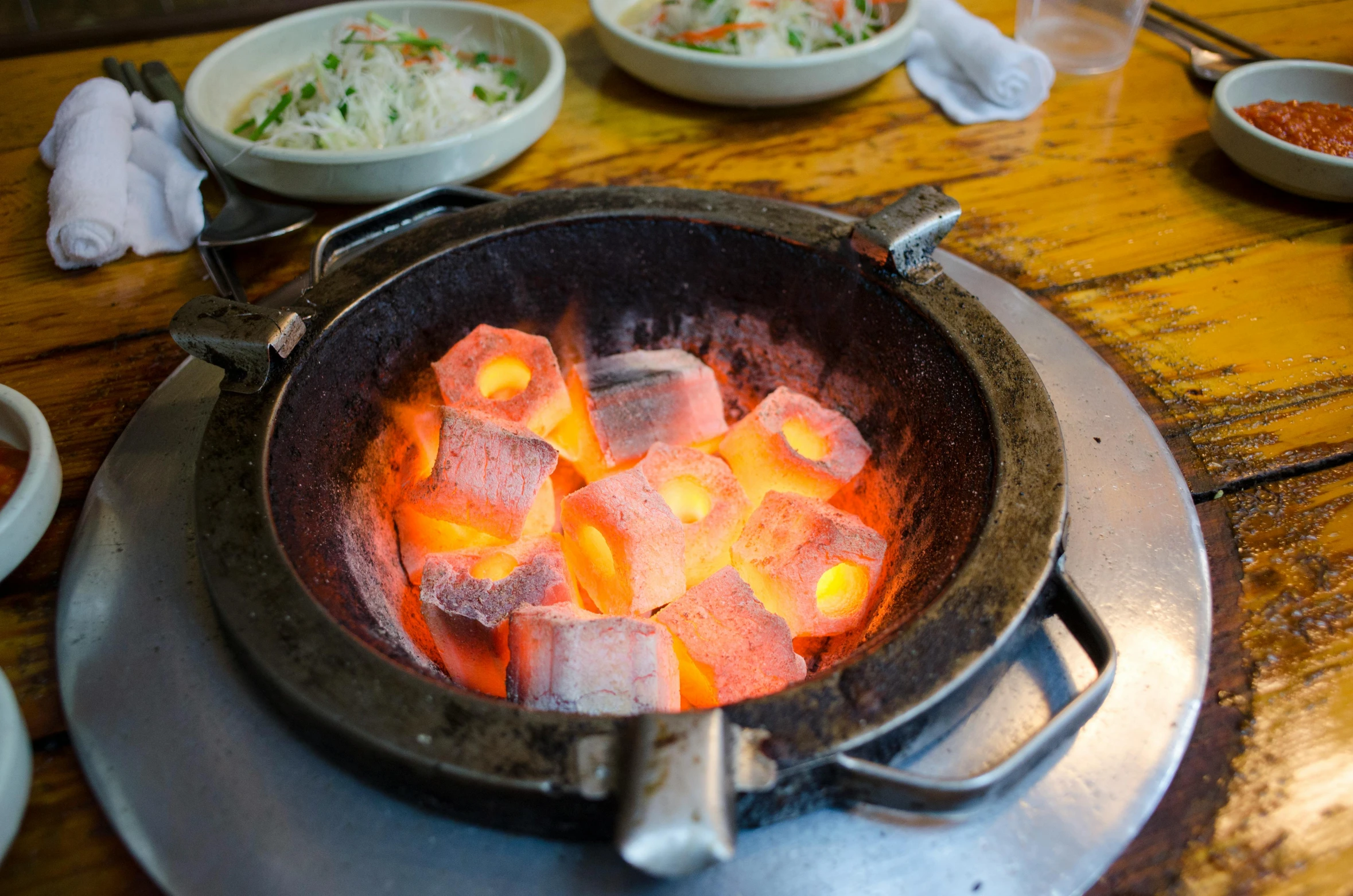 a pan filled with hot coal sitting on top of a wooden table, mingei, bao phan, glowing heating coils, square, thumbnail