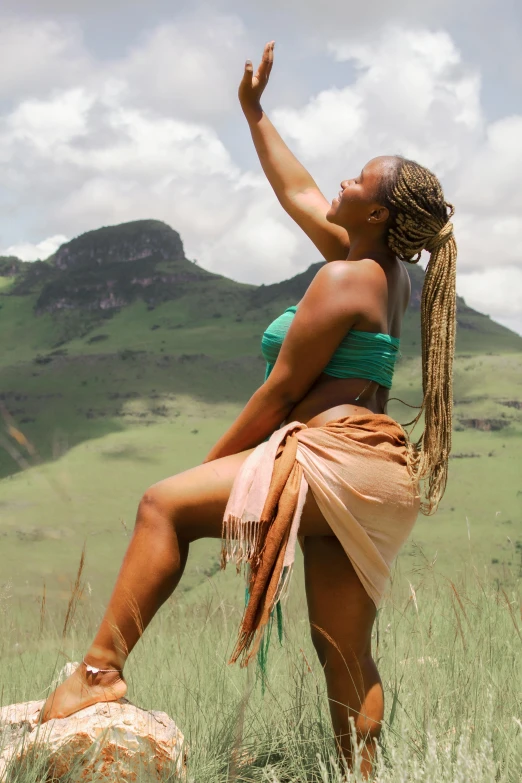 a woman standing on top of a rock in a field, loin cloth, wakanda, playful pose of a dancer, movie filmstill