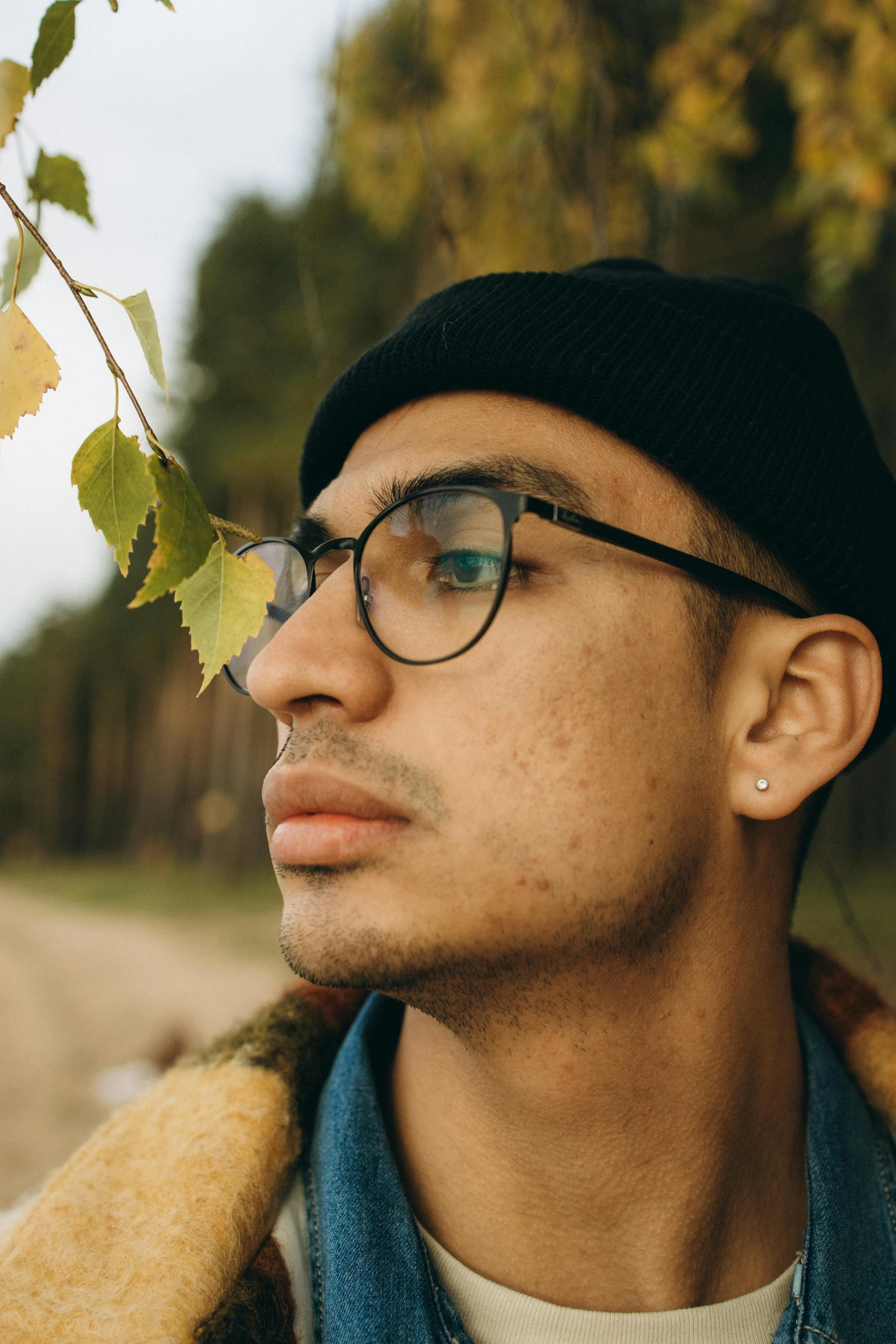 a man wearing glasses standing next to a tree, trending on pexels, visual art, androgynous face, mixed race, autumn, full frame image