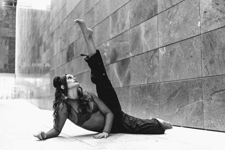 a black and white photo of a woman laying on the ground, arabesque, leaning against the wall, in an action pose, taken in the 2000s, alanis guillen