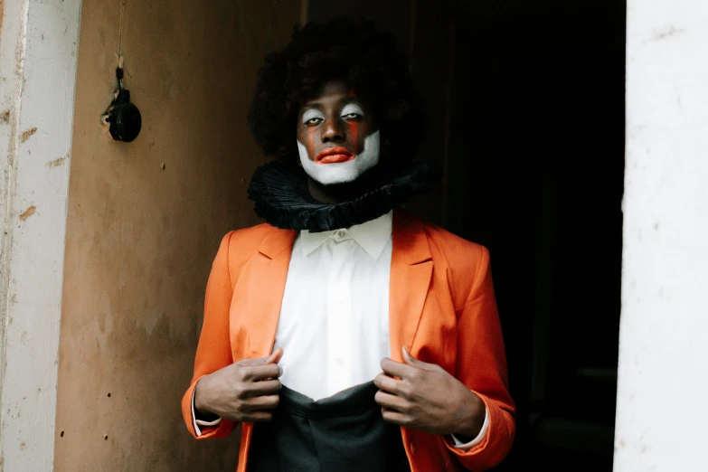 a man dressed as a clown standing in a doorway, an album cover, by Emanuel de Witte, pexels contest winner, orange skin, ( brown skin ), tuxedo, white facepaint