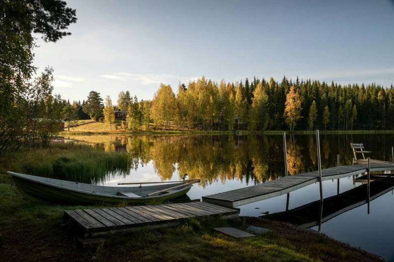 a couple of boats sitting on top of a lake, by Jesper Myrfors, hurufiyya, pine forests, boat dock, golden glow, lush surroundings