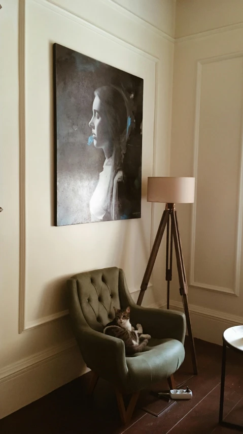 a living room with a chair and a painting on the wall, inspired by Emilio Grau Sala, pexels contest winner, figurative art, portrait of audrey hepburn, tripod, lara croft relaxing, low quality photo