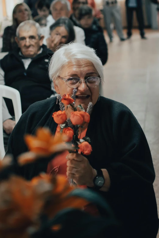 a group of elderly people sitting next to each other, an album cover, by Matteo Pérez, pexels contest winner, orange flowers, woman holding another woman, in australia, community celebration