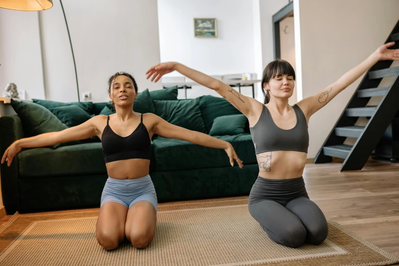 a couple of women sitting on top of a rug, trending on pexels, brunette fairy woman stretching, sport bra and shirt, slightly pixelated, low quality photo