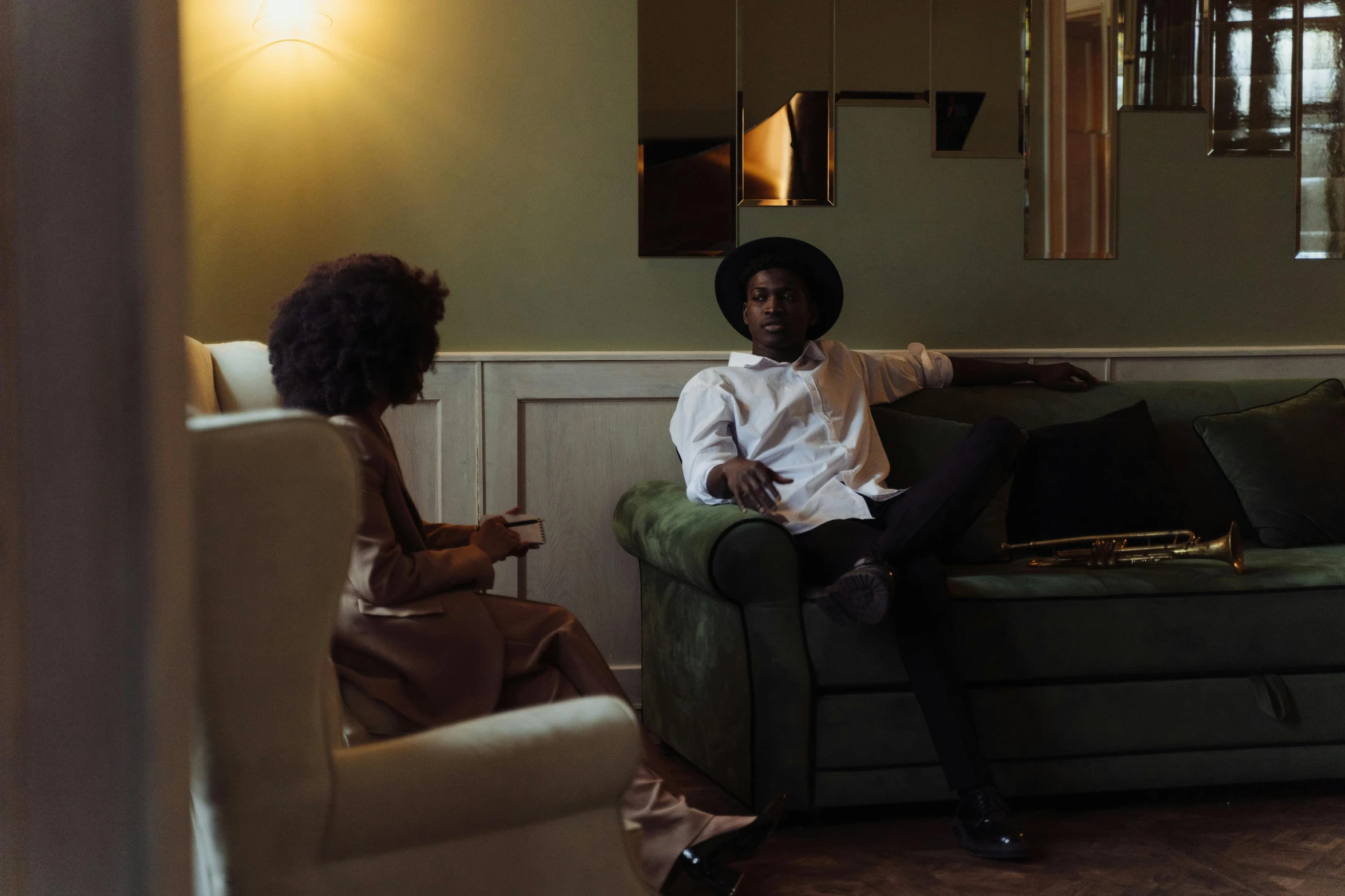 a man sitting on top of a green couch next to a woman, pexels contest winner, maria borges, dapper, looking around a corner, musician