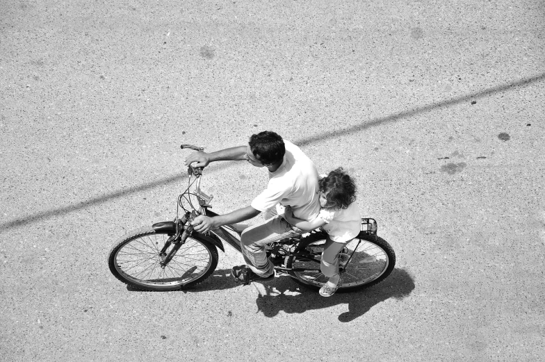 a man riding a bike next to a little girl, a photo, by Constantine Andreou, top down view, square, hot summer day, back and white