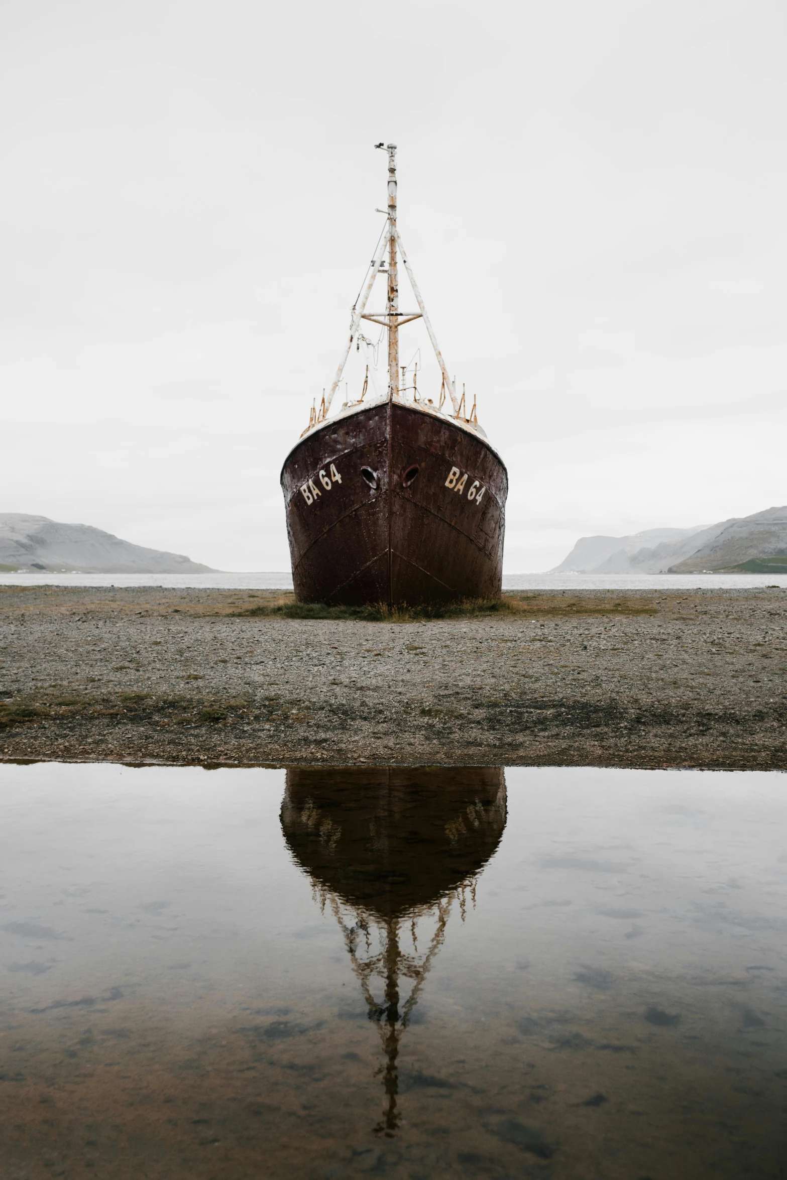 a large boat sitting on top of a body of water, inspired by Oluf Høst, unsplash contest winner, baroque, rusting, mirrored, iceland, beaching