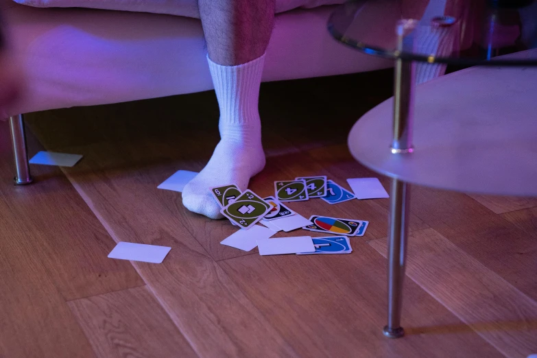 a person standing on top of a wooden floor next to a table, a hologram, pexels contest winner, process art, card game, overknee socks, broken lights, pair of keycards on table
