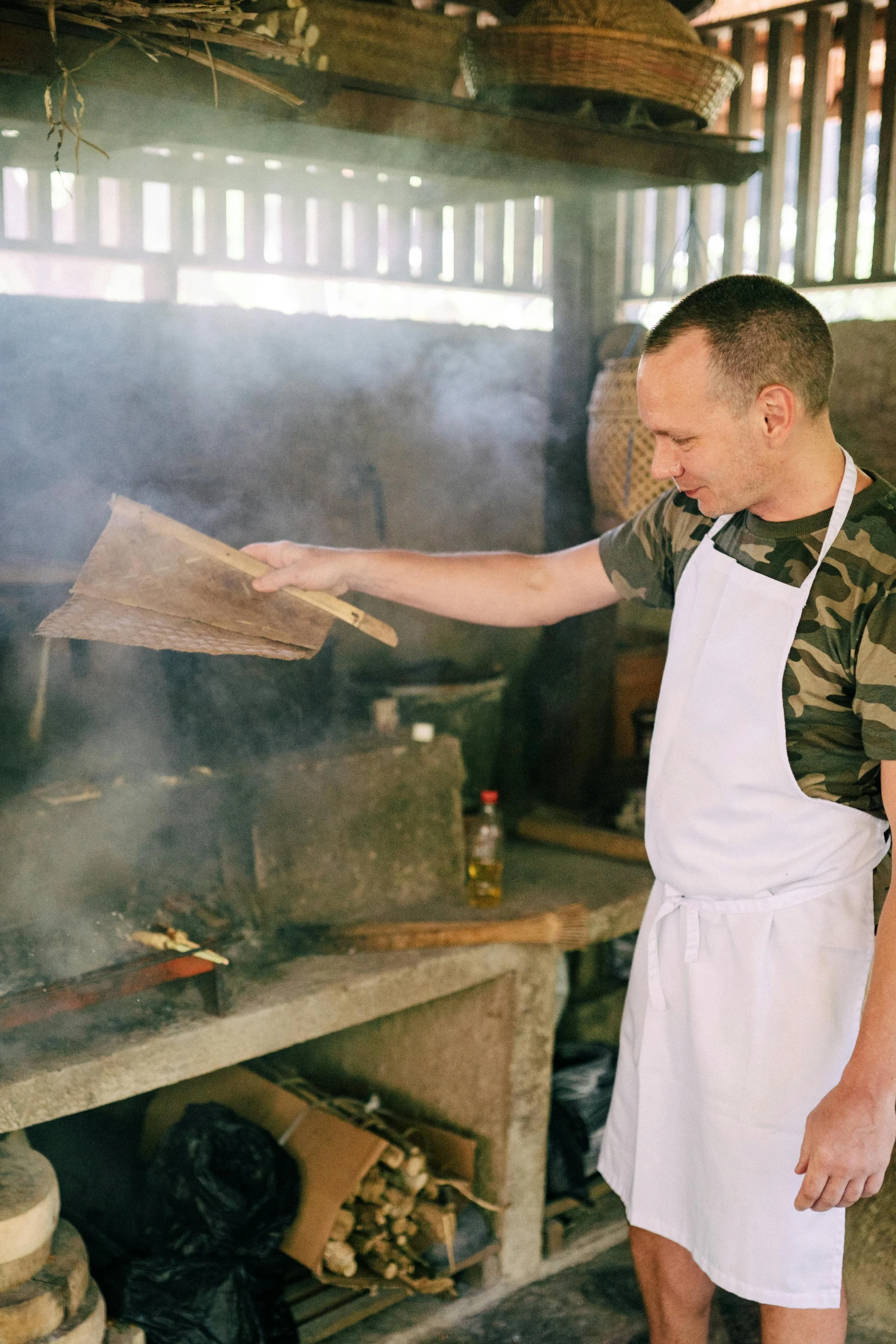 a man that is standing in front of a grill, made of bamboo, white apron, bosnian, smoked layered